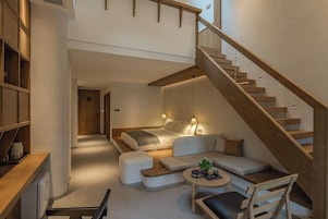 A modern interior with a staircase, a sofa, a coffee table, and a bookshelf.