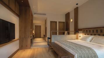 A hotel room with a bed, a bench, a TV, and wooden paneling.