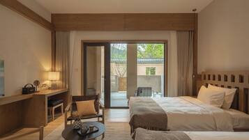 A hotel room with a bed, a desk, a chair, a table, and a view of the outdoors.