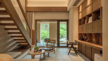 A modern interior with a staircase, seating area, and a bookshelf.