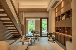 A modern interior with a staircase, seating area, and a bookshelf.