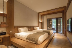 Un dormitorio moderno con dos camas, cabecero de madera, un televisor de pantalla plana y un balcón con vistas.