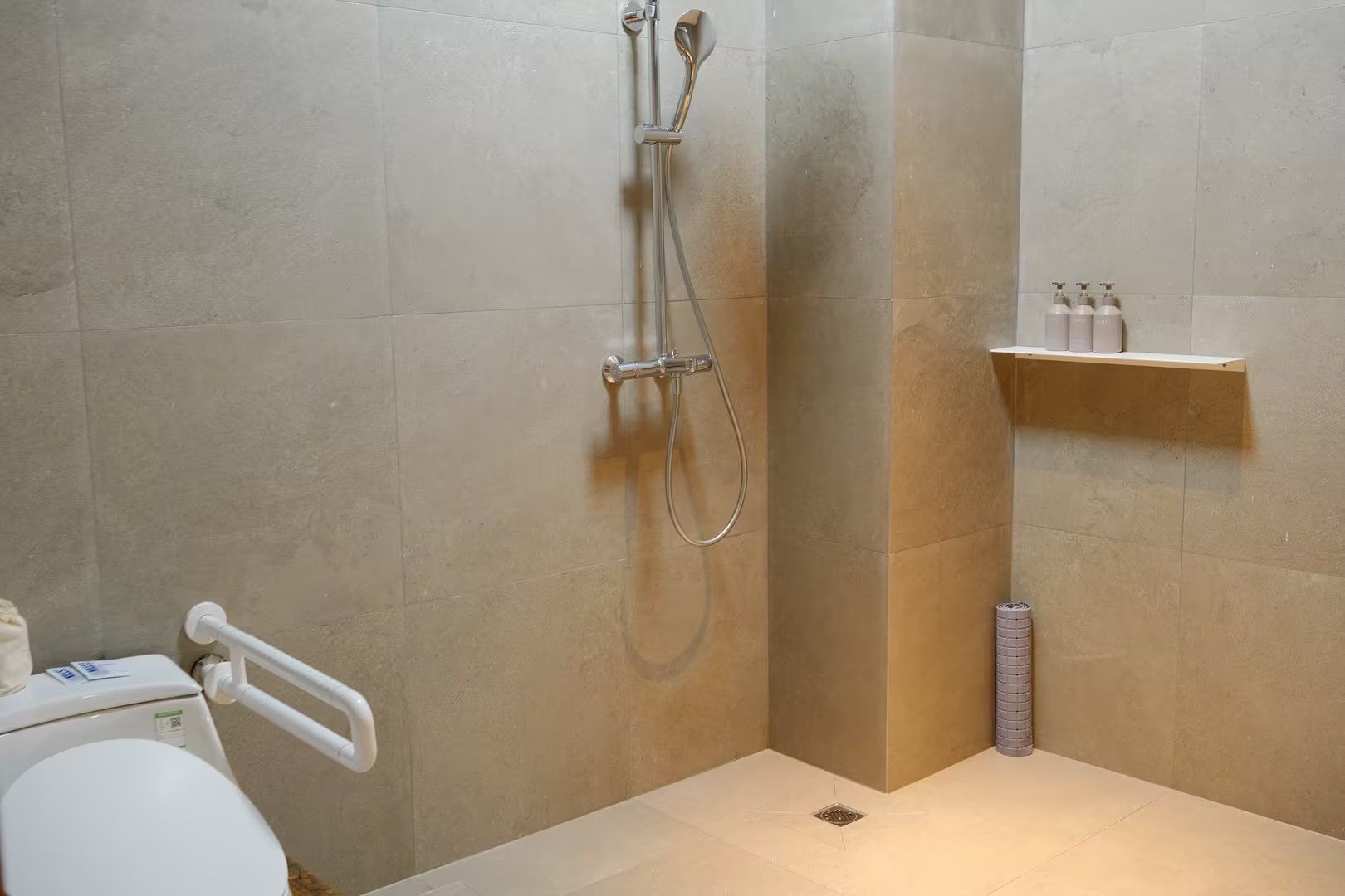 A bathroom with a shower, toilet, and a shelf with toiletries.