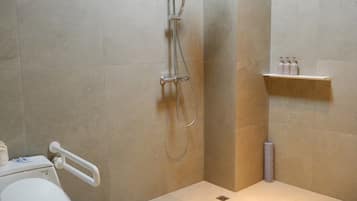 A bathroom with a shower, toilet, and a shelf with toiletries.