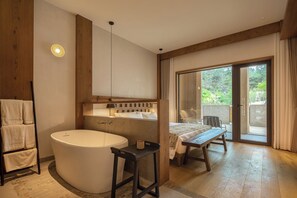 A modern bathroom with a large bathtub, a wooden bench, and a table with a view of the outdoors.