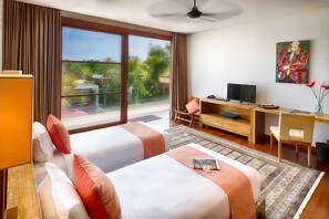 A hotel room with two beds, a desk, a television, and a view of greenery outside. - Casa Brio (Badung)