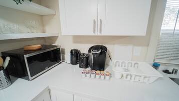 A kitchen with a microwave, toaster, coffee maker, and a tray of coffee pods.
