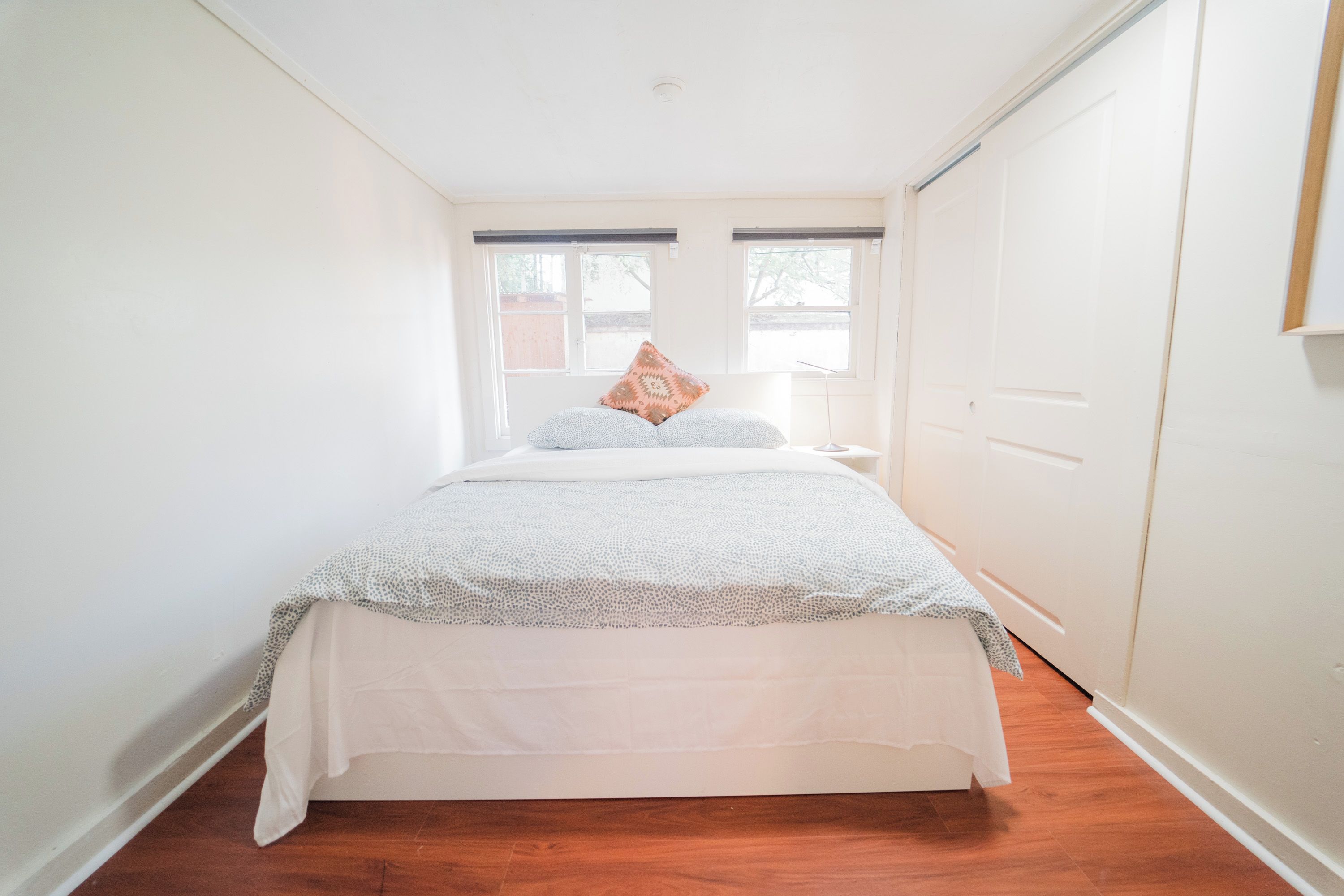 A narrow room with a bed, a window, and a door.