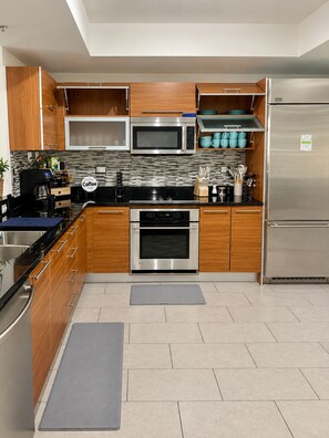 A modern kitchen with wooden cabinets, stainless steel appliances, and a tiled backsplash. - Spacius 3 bedroom-Ocean View Luxe Stay•Downtown Fort Myers•Pool •Spa (Fort Myers)