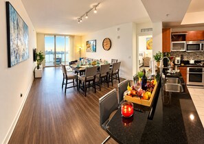 Apartamento moderno con comedor, cocina y un amplio ventanal con vista a un paisaje urbano.