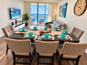 Uma sala de jantar com vista para o mar, um sofá e um relógio na parede.