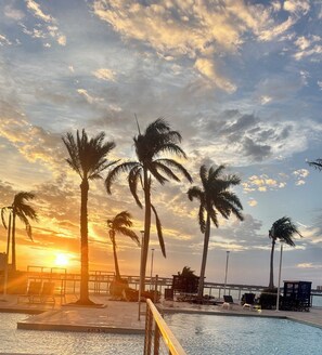 A poolside area with palm trees, a sunset, and a view of the water. - Spacius 3 bedroom-Ocean View Luxe Stay•Downtown Fort Myers•Pool •Spa (Fort Myers)