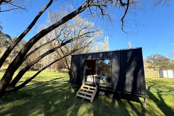 Une petite structure métallique noire, dotée d’une porte coulissante, d’une rampe en bois et offrant une vue dégagée sur l’intérieur.