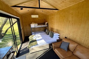 A compact room with a bunk bed, a sofa, and a large window.