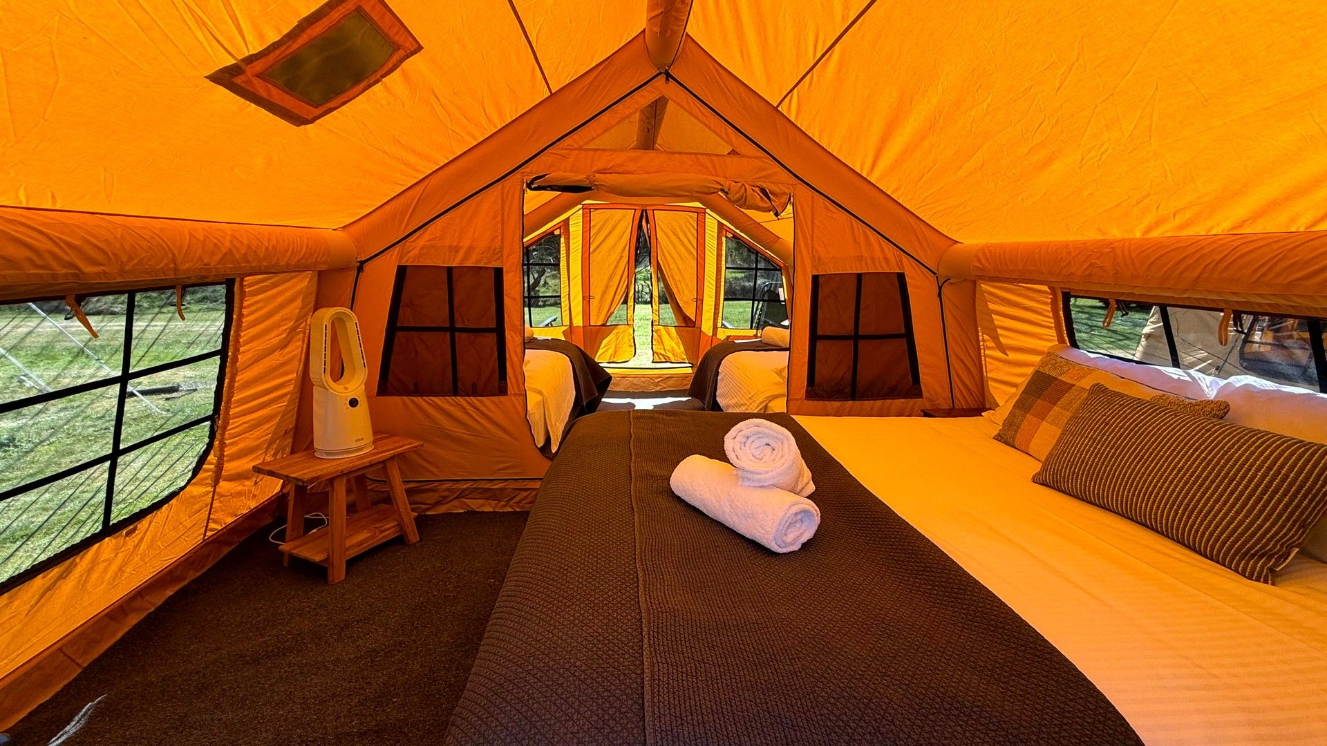 A tent with two beds, a table, and a chair.