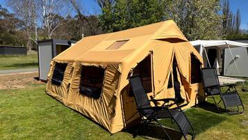 A camping tent with a peaked roof, a foldable chair, and a small portable table.