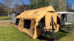 Une tente de camping avec un toit en forme de pyramide, une chaise pliante et une petite table portable.