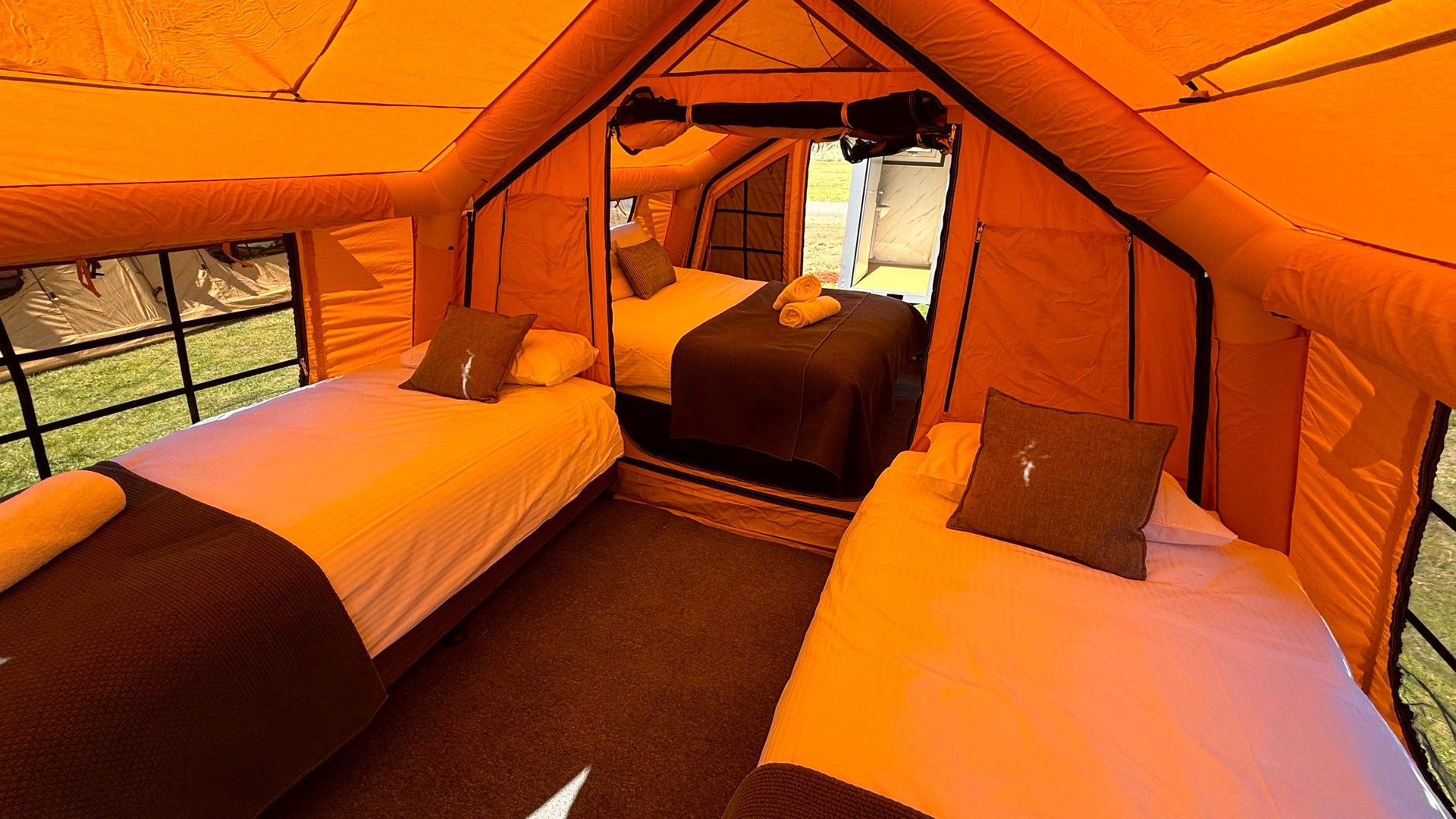 Una carpa con dos camas, una ventana y una puerta.
