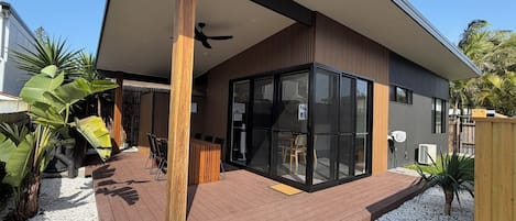 A modern house with a covered patio, large windows, and a ceiling fan.