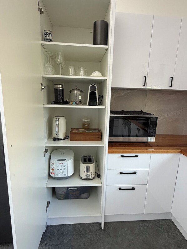 A kitchen with white cabinets, a microwave, a toaster, a kettle, and a coffee maker.