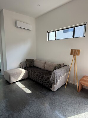 Una sala moderna con un sofá modular, una lámpara de pie y una ventana con vistas.