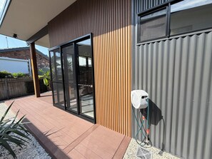A modern building with a large sliding glass door, a wooden panel wall, and a grey corrugated exterior.