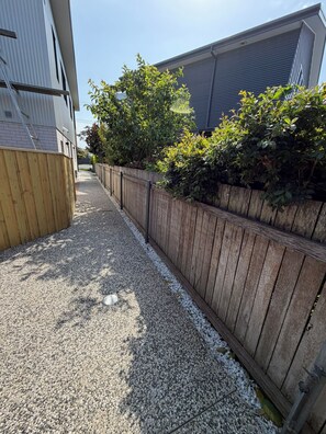 Un sendero de grava flanqueado por una cerca de madera y abundante vegetación.