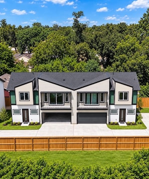 A modern two-story house with a garage, a front porch, and a fenced yard. - NEW 2BR Luxury Townhome Gated + Garage 10 Min DT (Houston)