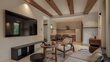 A modern living room with a flat-screen TV, a fireplace, and a kitchen in the background.