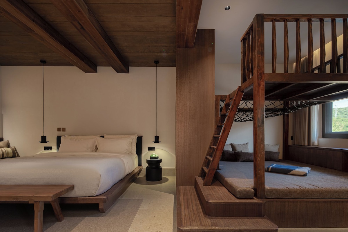 A bedroom with a bunk bed, a single bed, a wooden desk, and a nightstand.
