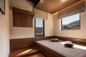 A room with a built-in bench, a window with a view of a landscape, and a wall-mounted shelf.