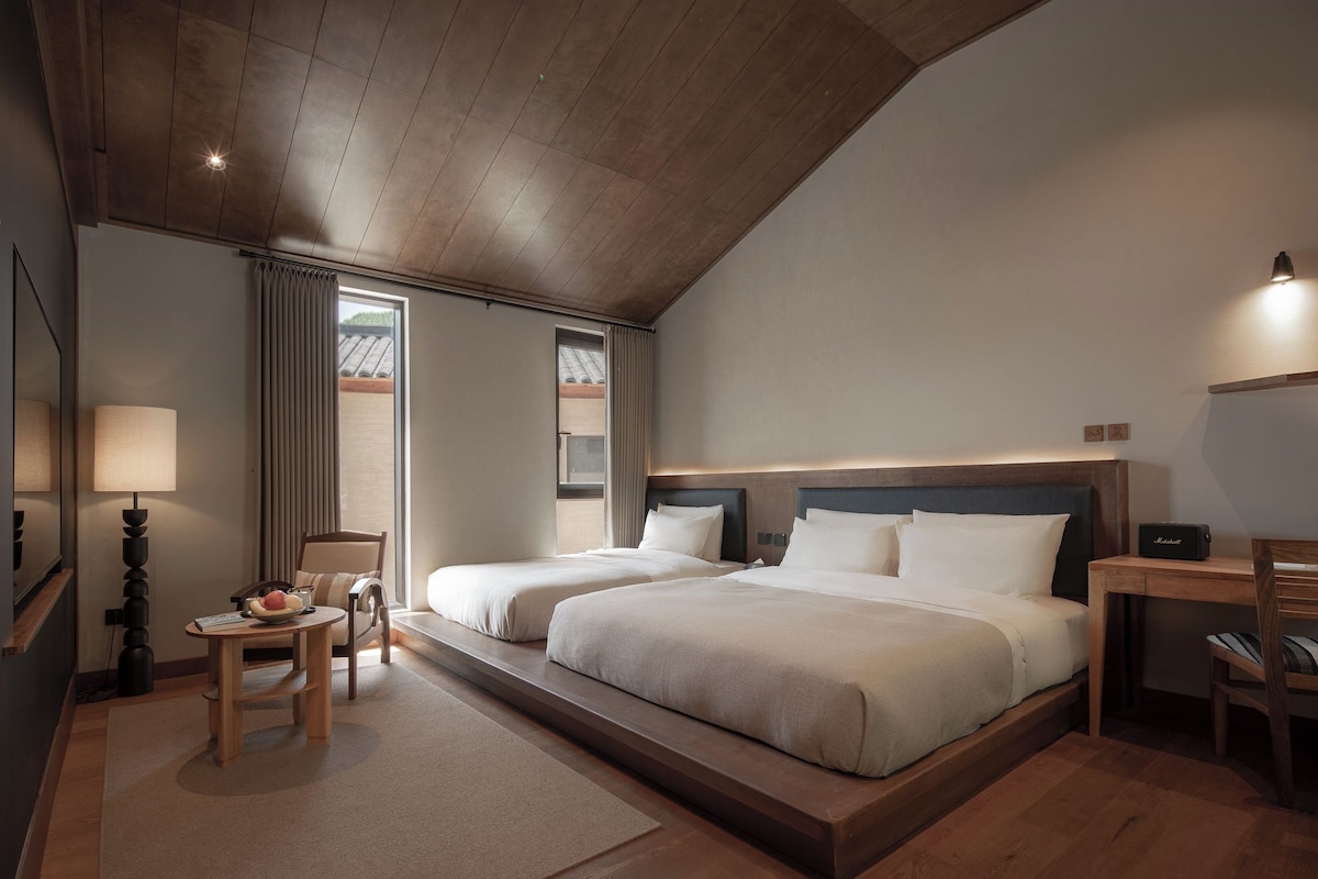 A hotel room with a large bed, bedside tables, a desk, and a chair.