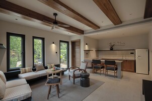 Uma sala de estar moderna com sofá, cadeiras, mesa de jantar e cozinha equipada com frigorífico e pia.