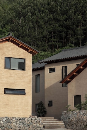 Un edificio moderno con un acceso de pared de piedra, varios ventanales y un techo inclinado.