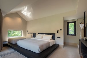 Un dormitorio con una cama grande, dos mesitas de noche, una ventana y una lámpara de techo.