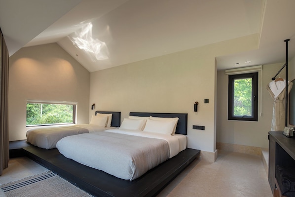 A bedroom with a large bed, two bedside tables, a window, and a ceiling light.
