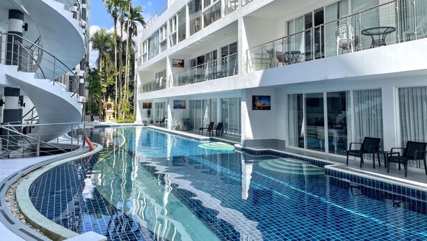 A cruise ship with a swimming pool, multiple balconies, and palm trees. - B8 - 2 Bedrooms Serviced Apartment with pool view, Karon Beach (Tambon Karon)