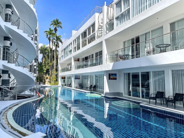 A cruise ship with a swimming pool, multiple balconies, and palm trees. - B8 - 2 Bedrooms Serviced Apartment with pool view, Karon Beach (Tambon Karon)