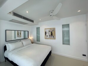 Un dormitorio moderno con una cama grande, un ventilador de techo, un respiradero de pared y dos obras de arte enmarcadas.