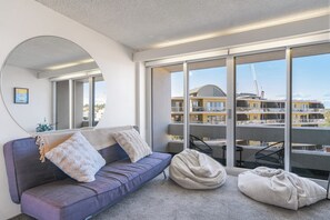 A modern living room with a sofa, bean bag, and a large mirror. - Manly beach: Everything minutes away! (Manly)