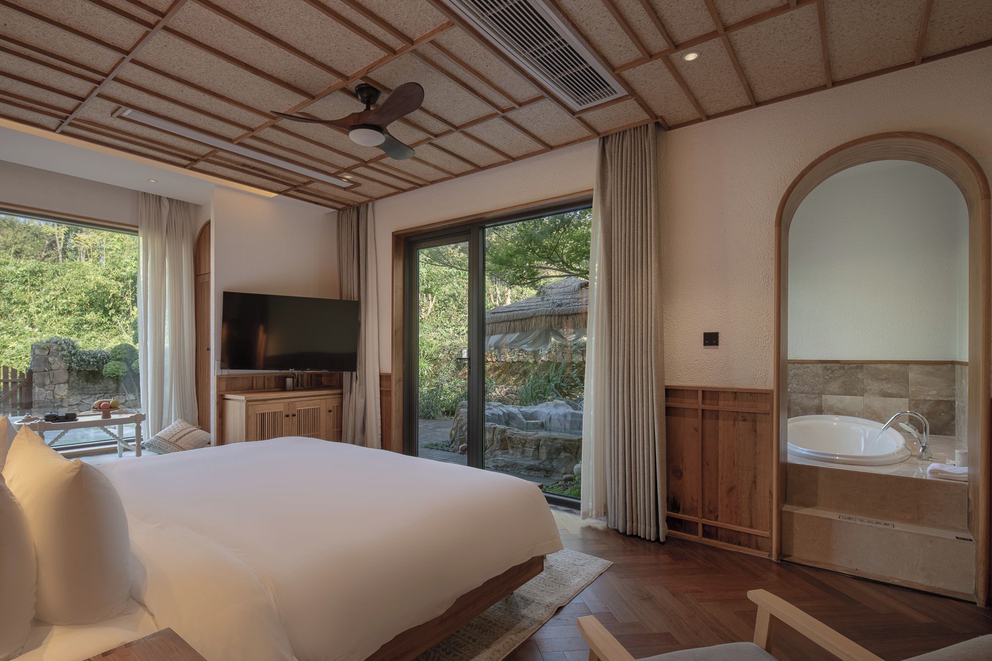 Une chambre dotée d’un grand lit, d’une télévision, d’une salle de bain avec baignoire et offrant une vue sur l’extérieur.