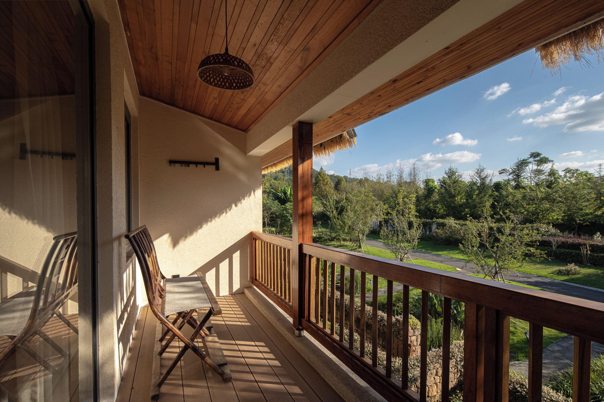 Eine Holzterrasse mit Geländer, einer Bank und einer hängenden Leuchte.
