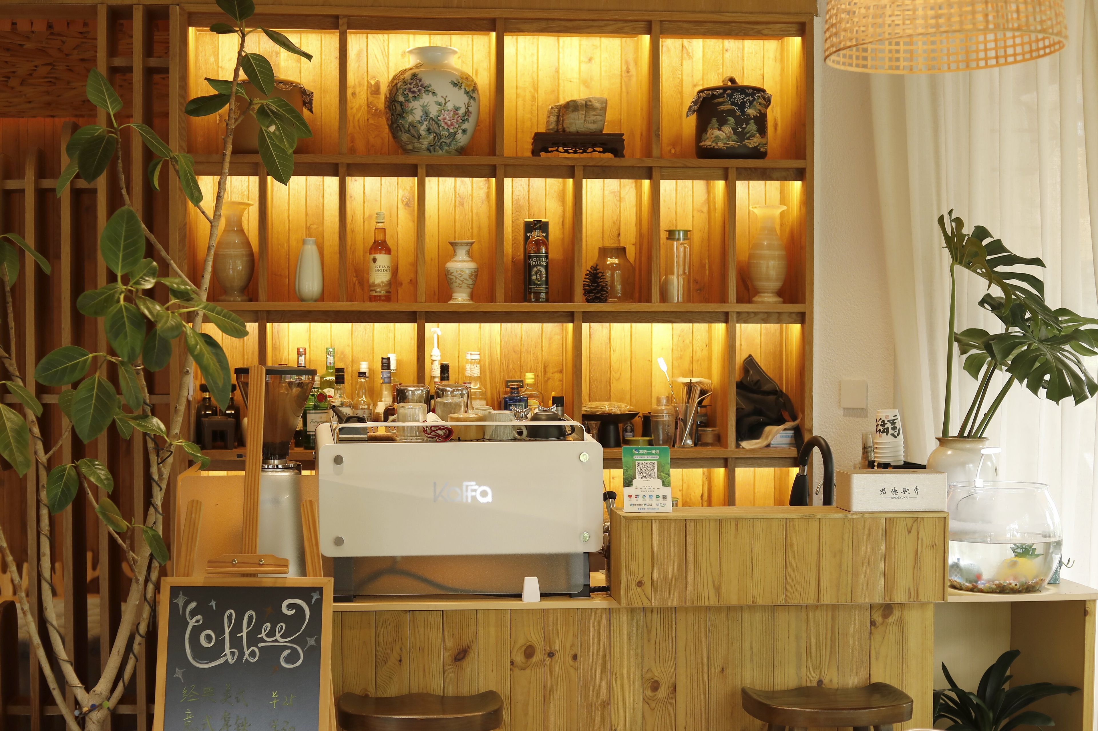 Interior de una cafetería con estanterías de madera, una máquina de café y varios objetos decorativos.