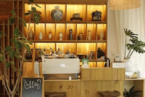 Interior d'una cafeteria amb prestatges de fusta, una màquina de cafè i diversos objectes decoratius.