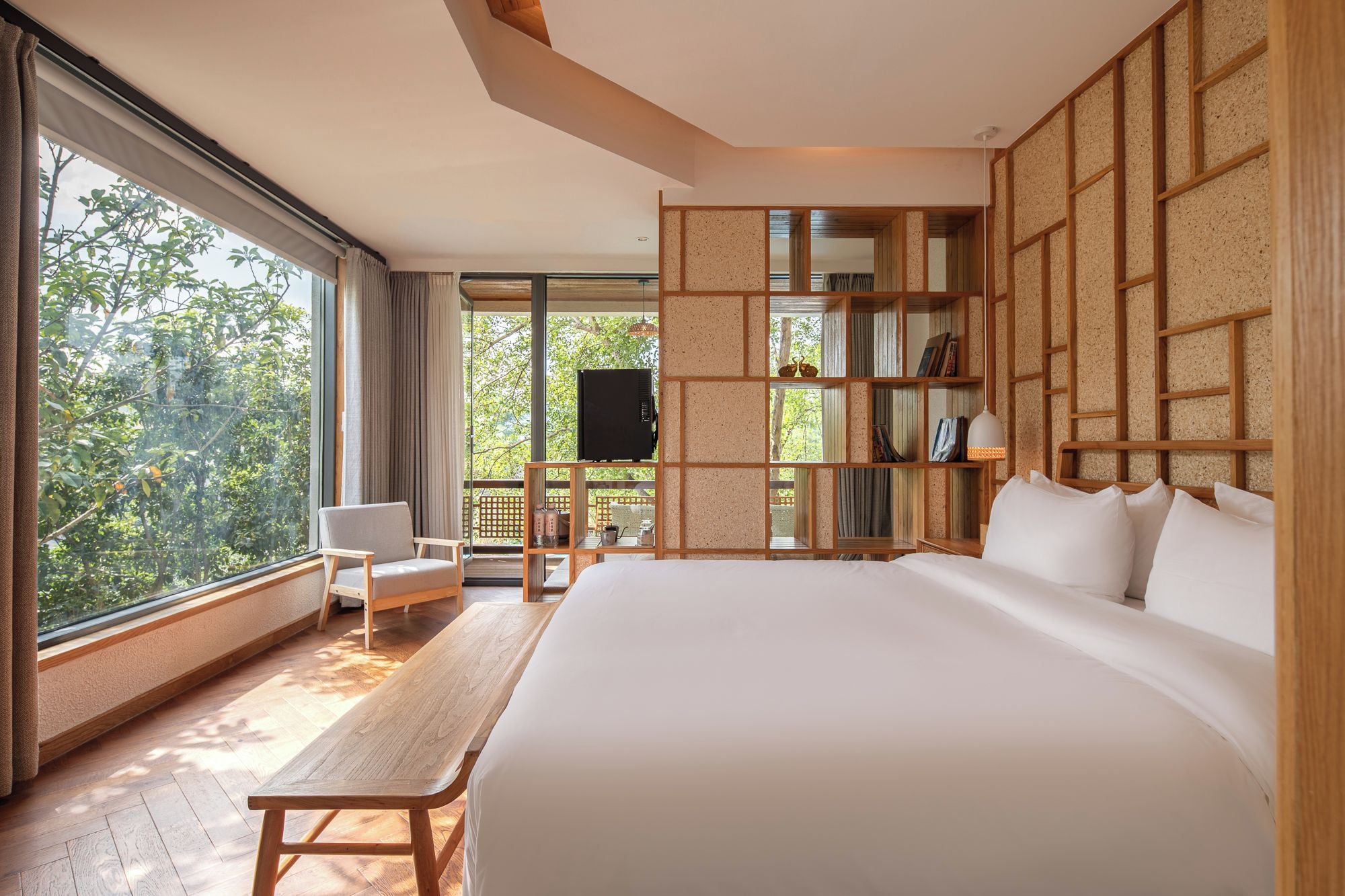 Un dormitorio con una cama grande, un escritorio de madera, una silla, un televisor y una estantería.