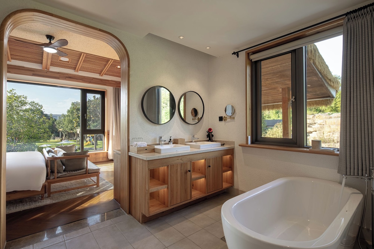 A modern bathroom with a freestanding bathtub, a double sink vanity, and a large mirror.