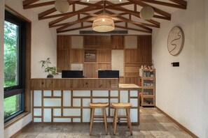 A reception area with wooden paneling, two bar stools, a desk with a laptop, and a hanging light fixture.