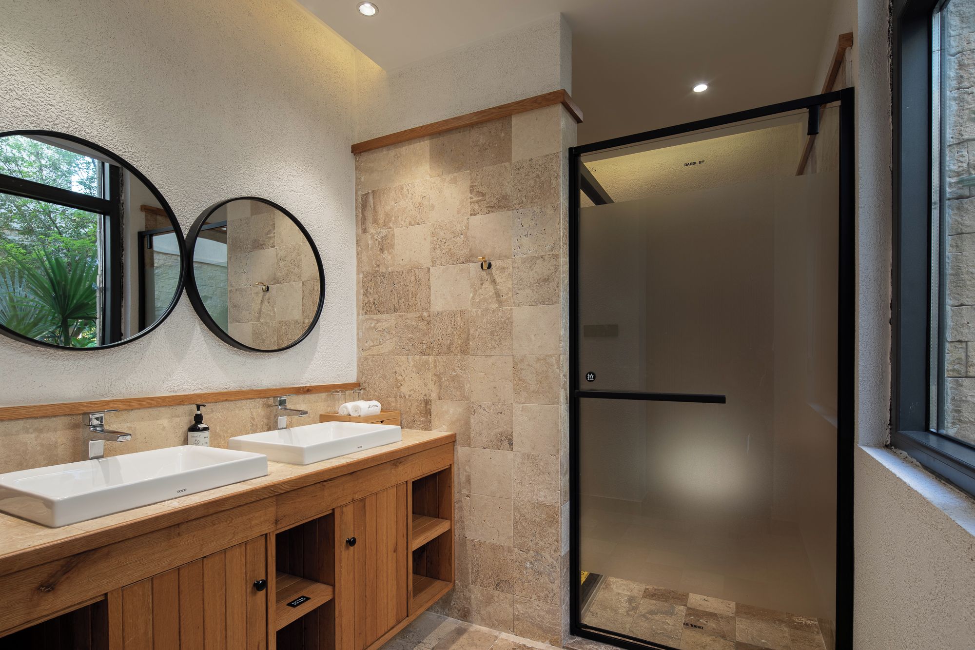 Un baño con dos lavamanos, un espejo y una ducha con cerramiento de vidrio.