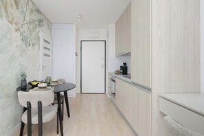 A compact kitchen with a dining area, a white door, and a light-colored floor. - Warsaw | Krochmalna 61 | Modern Studio | Air-conditioning (Warszawa)