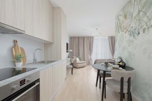 A modern kitchen with a built-in oven, a dining area with a table and chairs, and a living space with a sofa and curtains. - Warsaw | Krochmalna 61 | Modern Studio | Air-conditioning (Warszawa)